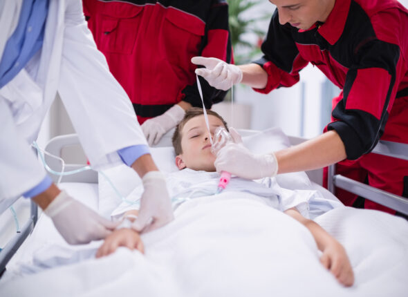 Doctors adjusting oxygen mask while rushing the patient in emergency room at hospital
