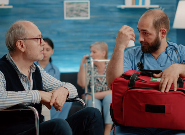 Medical assistant giving bottle of pills to retired patient